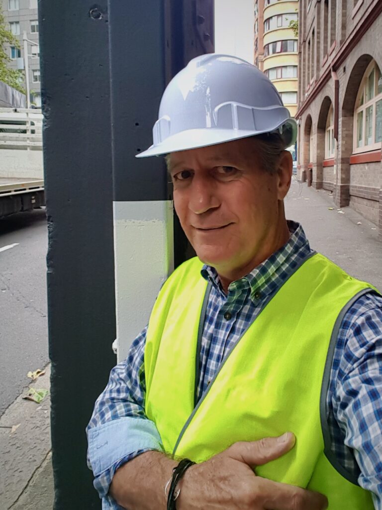 Lance wearing a neon yellow-green vest and a white hard hat.