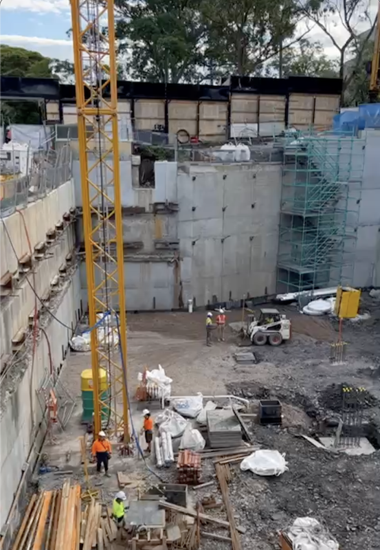 Construction below ground level with crew members and materials scattered about.