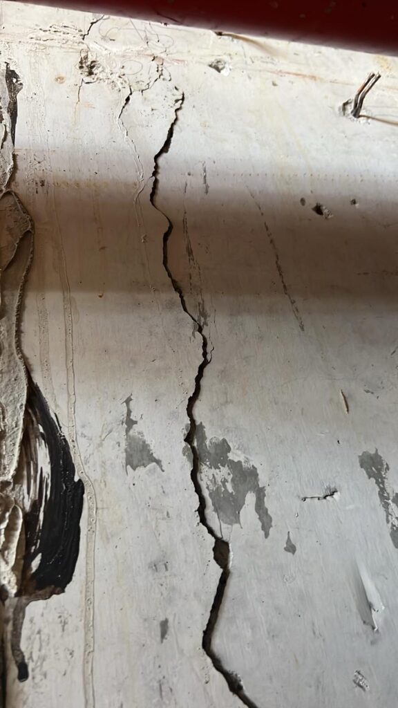 A large vertical crack along a concrete wall.