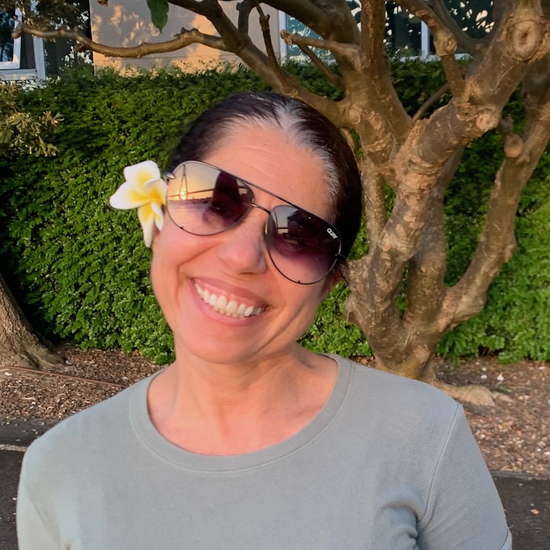 Tammy wearing sunglasses with a flower behind her ear.